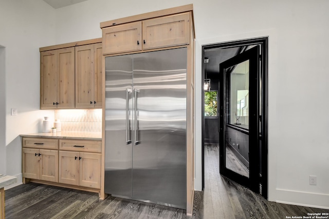 kitchen with dark hardwood / wood-style floors, backsplash, light brown cabinets, and built in fridge