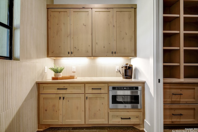 bar featuring stainless steel oven and light brown cabinetry