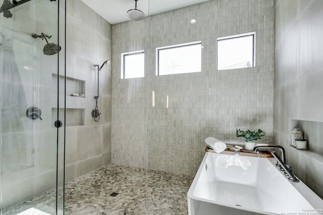 bathroom featuring tile walls, a shower with door, and sink