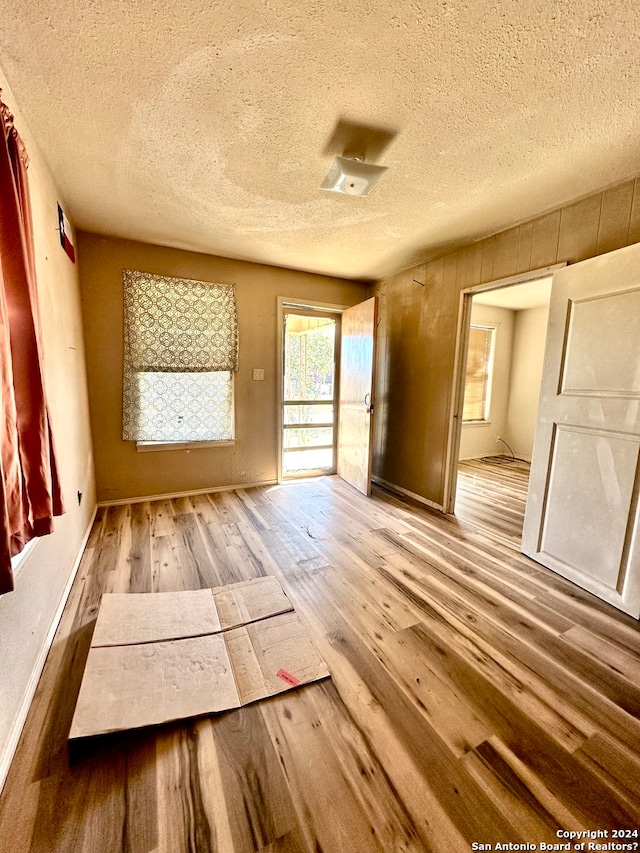 unfurnished room featuring a textured ceiling and light hardwood / wood-style flooring