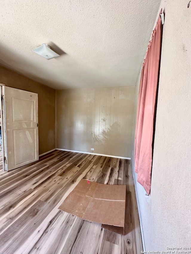 unfurnished room with a textured ceiling and dark hardwood / wood-style floors