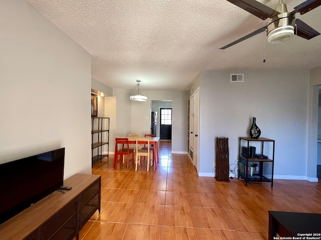 dining area with light tile floors, ceiling fan, and a textured ceiling