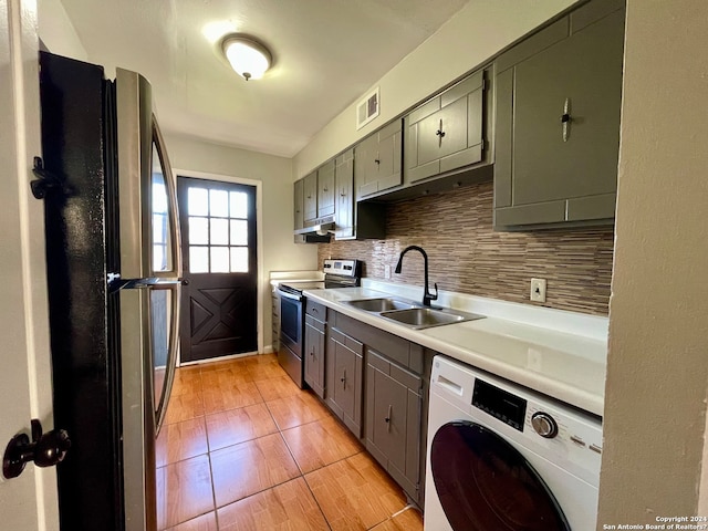 kitchen with stainless steel appliances, light tile floors, tasteful backsplash, washer / dryer, and sink