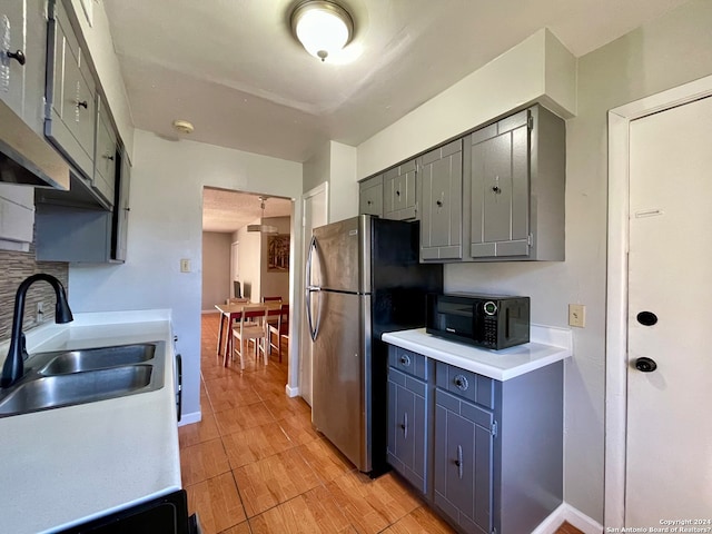 kitchen with stainless steel fridge, sink, light tile floors, gray cabinets, and backsplash