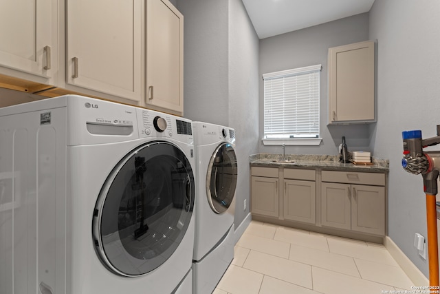 laundry area featuring light tile flooring, sink, washing machine and dryer, and cabinets