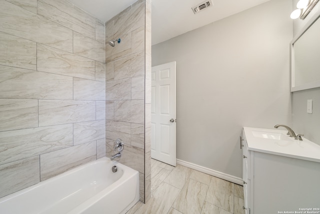 bathroom featuring tile floors, vanity, and tiled shower / bath