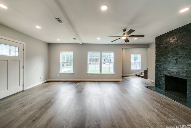 unfurnished living room with dark wood-type flooring, a fireplace, and a healthy amount of sunlight