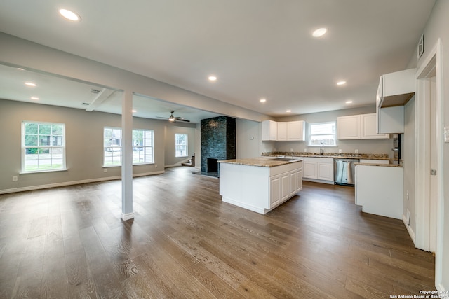 kitchen with stainless steel dishwasher, a fireplace, ceiling fan, white cabinetry, and dark hardwood / wood-style floors