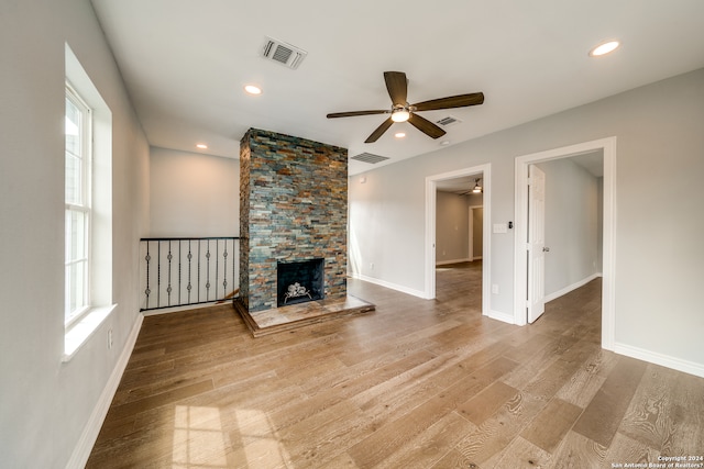 unfurnished living room featuring plenty of natural light, a fireplace, ceiling fan, and light hardwood / wood-style flooring