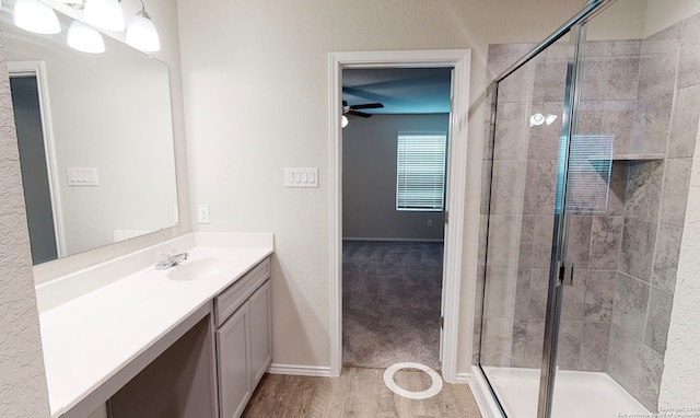 bathroom with ceiling fan, hardwood / wood-style floors, vanity, and walk in shower