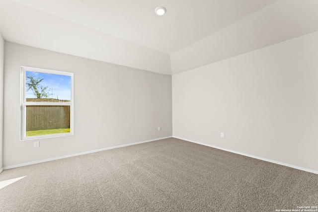 carpeted spare room featuring lofted ceiling