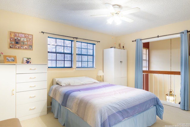 carpeted bedroom with ceiling fan and a textured ceiling