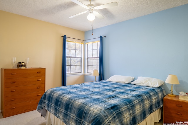 bedroom with a textured ceiling, light colored carpet, and ceiling fan