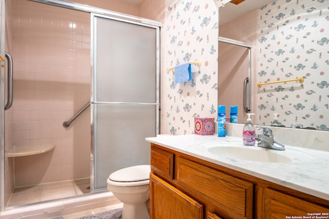 bathroom featuring oversized vanity, toilet, a shower with shower door, and tile flooring