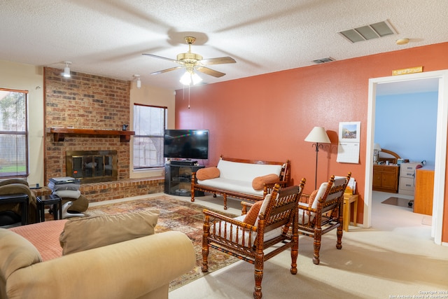 living room featuring a brick fireplace, a textured ceiling, light colored carpet, and ceiling fan