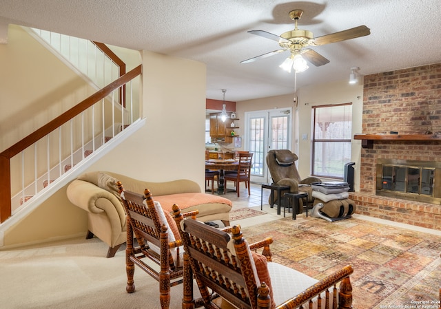 living room with a fireplace, a textured ceiling, ceiling fan, and light colored carpet