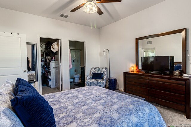 bedroom featuring connected bathroom, ceiling fan, light carpet, and a closet