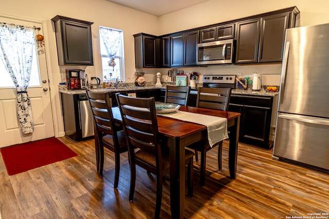 kitchen featuring dark brown cabinets, light stone countertops, appliances with stainless steel finishes, and dark hardwood / wood-style flooring