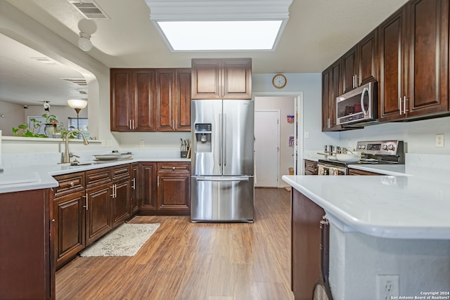 kitchen with stainless steel appliances, light hardwood / wood-style floors, sink, and kitchen peninsula