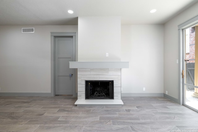 unfurnished living room featuring light hardwood / wood-style floors and a tiled fireplace