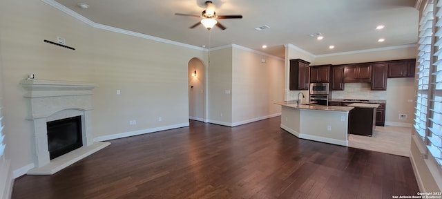 kitchen featuring ceiling fan, dark brown cabinets, dark hardwood / wood-style floors, and an island with sink