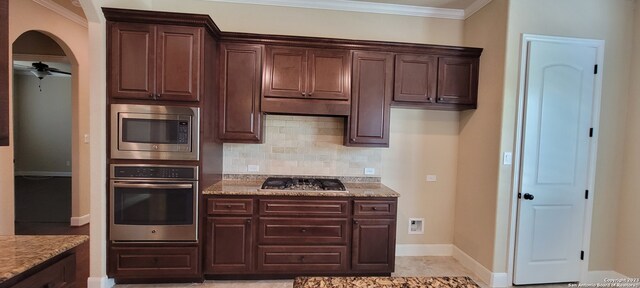 kitchen with backsplash, ceiling fan, stainless steel appliances, light tile floors, and light stone counters