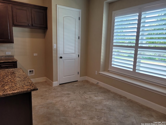 kitchen with backsplash, light tile floors, and dark stone counters