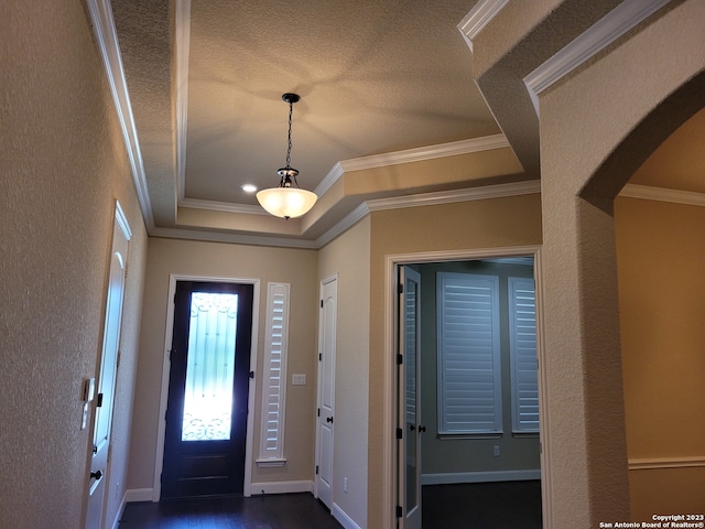 entrance foyer featuring dark wood-type flooring, ornamental molding, a textured ceiling, and a tray ceiling