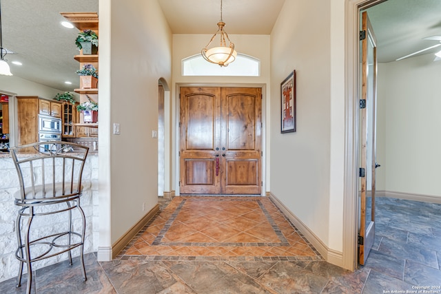 entrance foyer with a textured ceiling, dark tile flooring, and ceiling fan