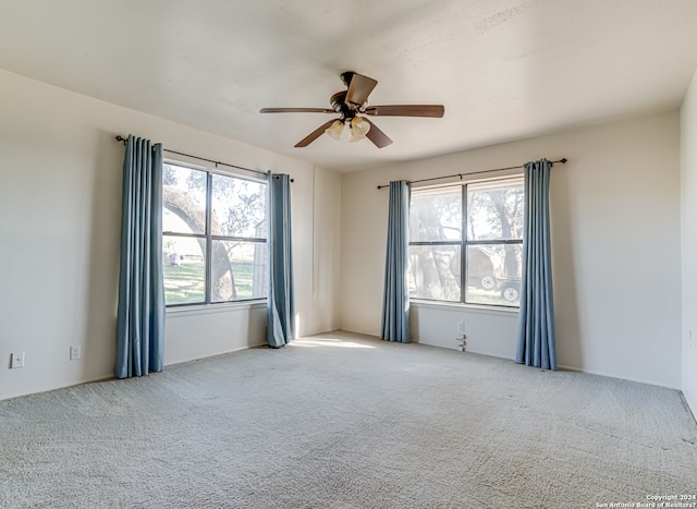 empty room featuring light carpet, a healthy amount of sunlight, and ceiling fan