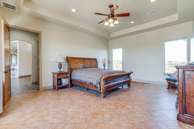 tiled bedroom featuring a raised ceiling and ceiling fan