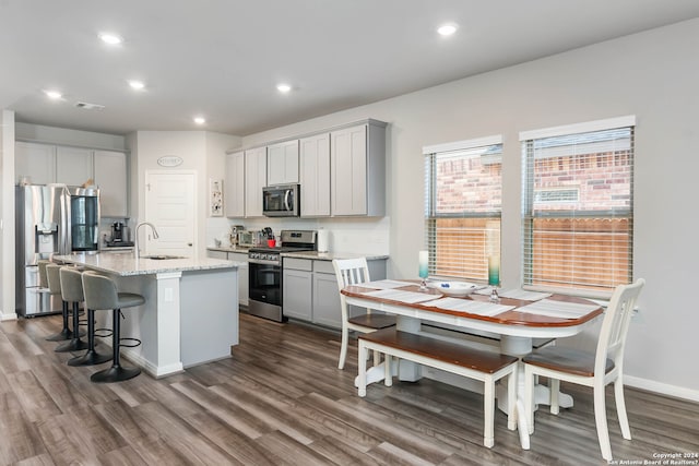 kitchen featuring gray cabinetry, a kitchen island with sink, appliances with stainless steel finishes, and sink