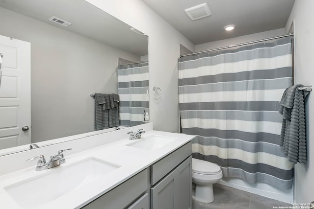 bathroom featuring tile flooring, toilet, and dual bowl vanity