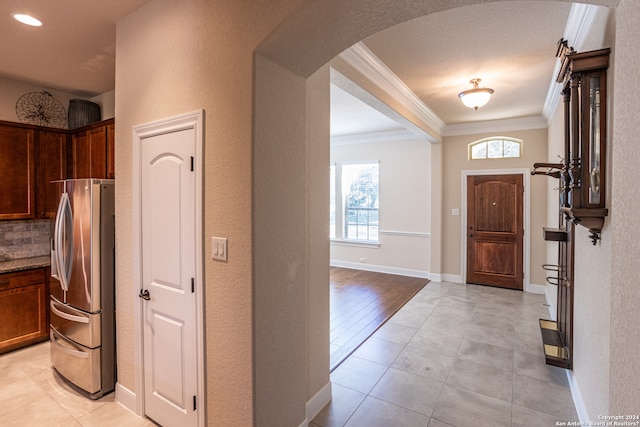 foyer entrance with light tile floors, a textured ceiling, and crown molding