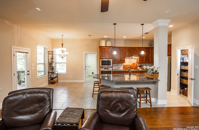 tiled living room featuring sink and ceiling fan with notable chandelier