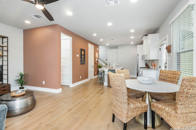 dining area with ceiling fan, sink, and light wood-type flooring