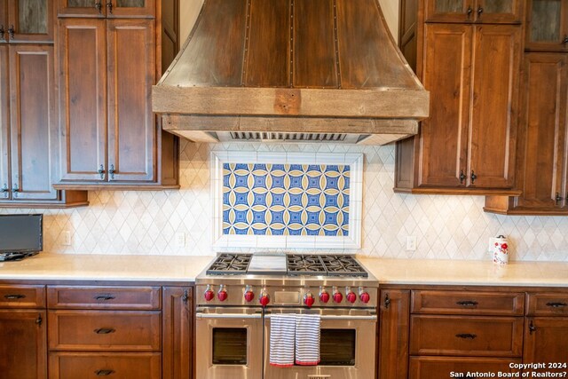 kitchen featuring range with two ovens, backsplash, and custom range hood