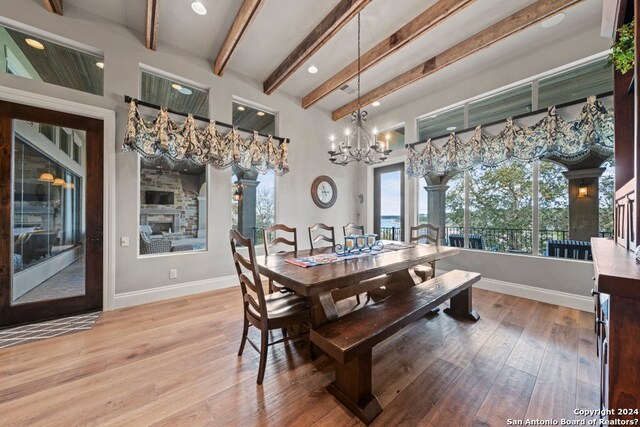 dining area with beam ceiling, light wood-type flooring, and an inviting chandelier