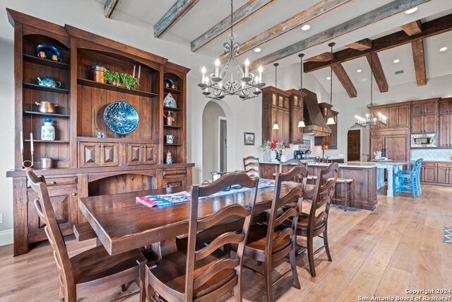 dining area with a chandelier, light hardwood / wood-style floors, and lofted ceiling with beams