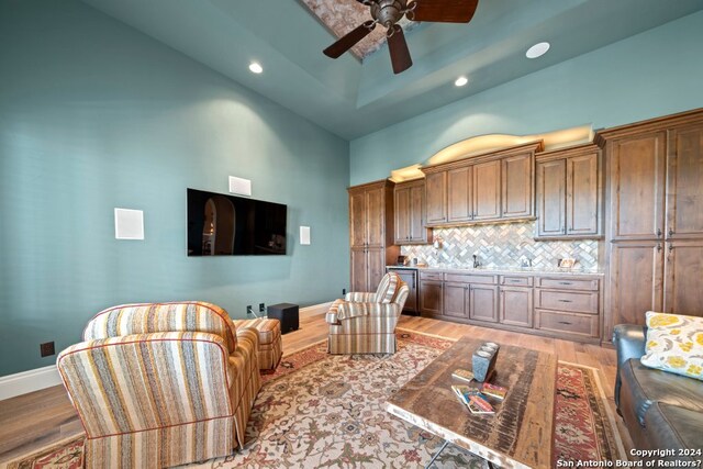 living room featuring high vaulted ceiling, light hardwood / wood-style floors, ceiling fan, and sink