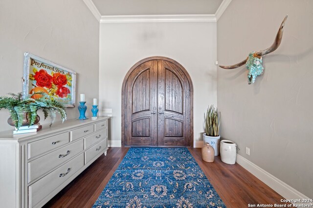 foyer entrance with crown molding and dark hardwood / wood-style flooring