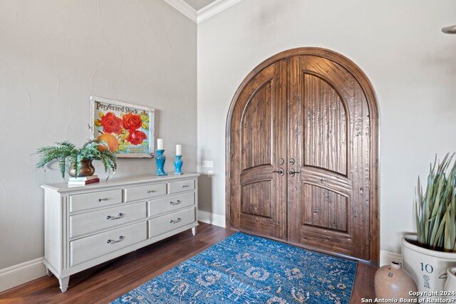 foyer with ornamental molding and dark hardwood / wood-style floors