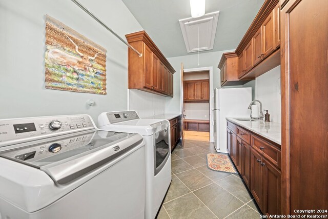 laundry room featuring separate washer and dryer, tile floors, cabinets, and sink