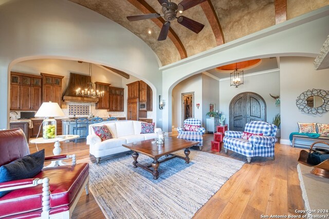 living room with hardwood / wood-style floors, high vaulted ceiling, and ceiling fan with notable chandelier