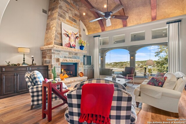 living room featuring a fireplace, high vaulted ceiling, ceiling fan, and light wood-type flooring