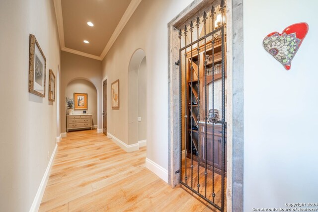 hall with crown molding and light hardwood / wood-style floors