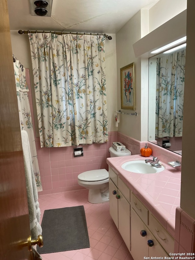 bathroom with tile walls, toilet, tile floors, and vanity