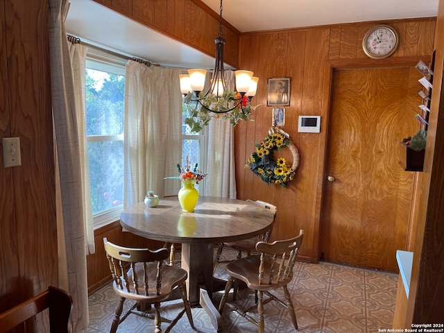 tiled dining space featuring wood walls and a chandelier