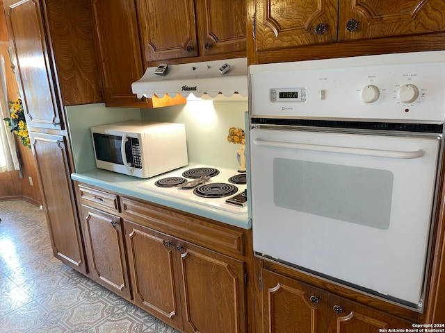 kitchen featuring white appliances, fume extractor, and light tile floors