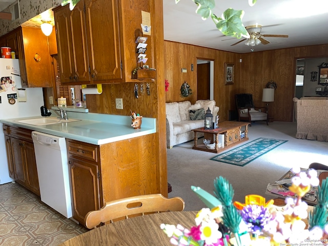 kitchen featuring ceiling fan, wood walls, dishwasher, sink, and light carpet